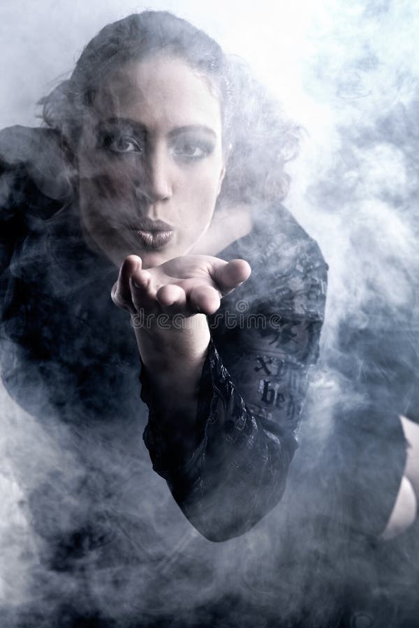 Woman with long curly hair blowing smoke stock photos