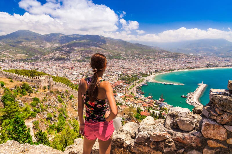 Woman look on landscape of Alanya with marina and Kizil Kule red tower in Antalya district, Turkey, Asia. Famous tourist