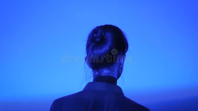 Woman looking around at modern exhibition with multi color light illumination