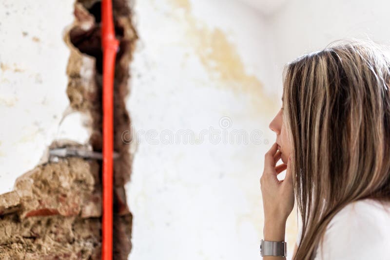 Woman looking at damage after a water pipe leak. Destruction, maintenance.