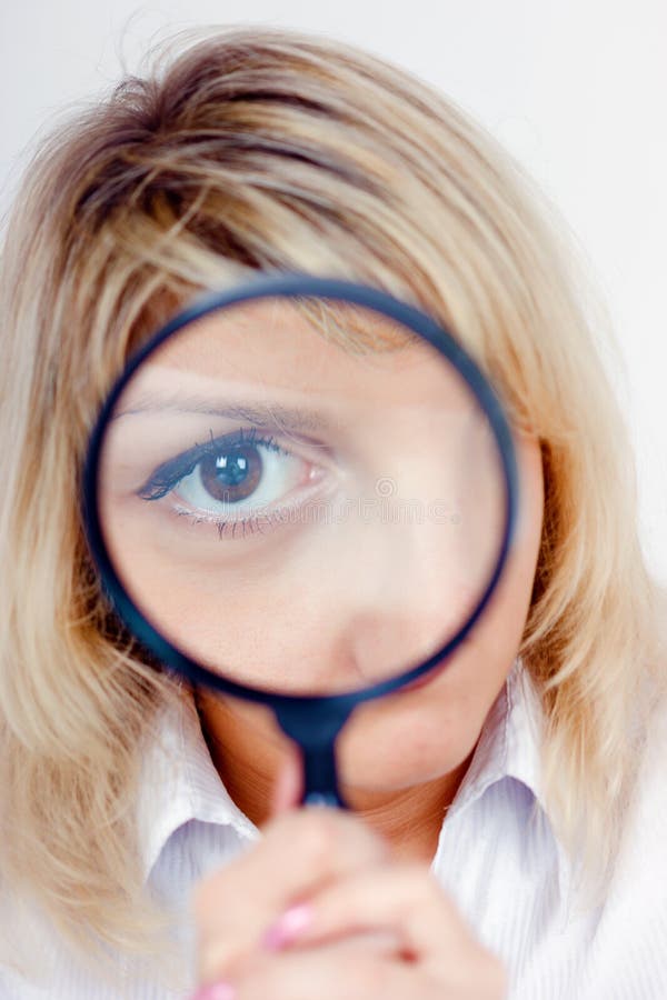 Young woman with magnifying glass in front of her eye