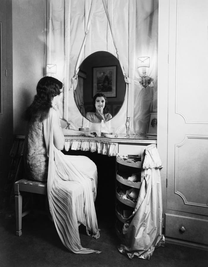 Woman looking in mirror at dressing table.