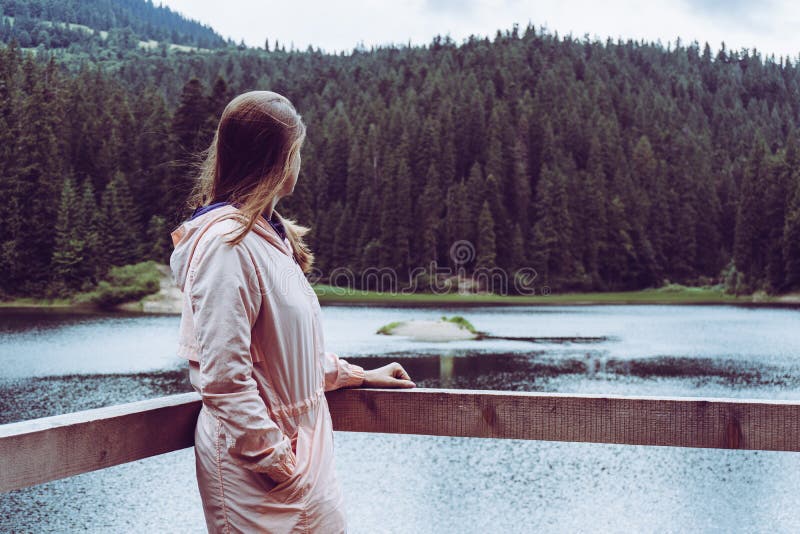 Woman looking at mountain lake with forest behind