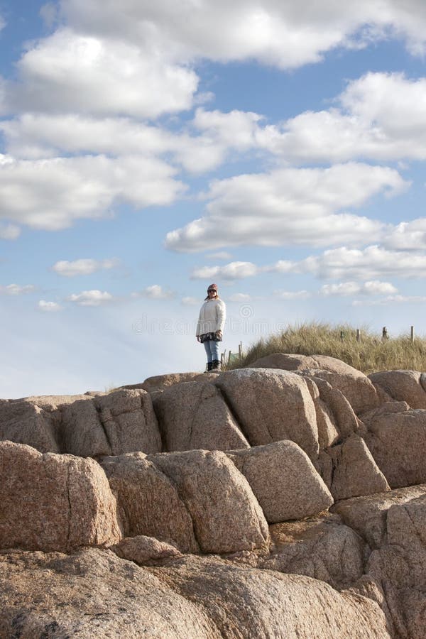 Woman looking out to sea a top of old rock formation