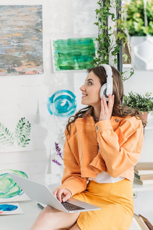 Woman Looking at Paintings on Wall while Listening Music in Headphones
