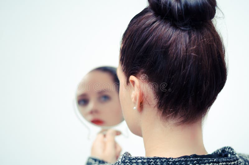 Woman looking at self reflection in mirror