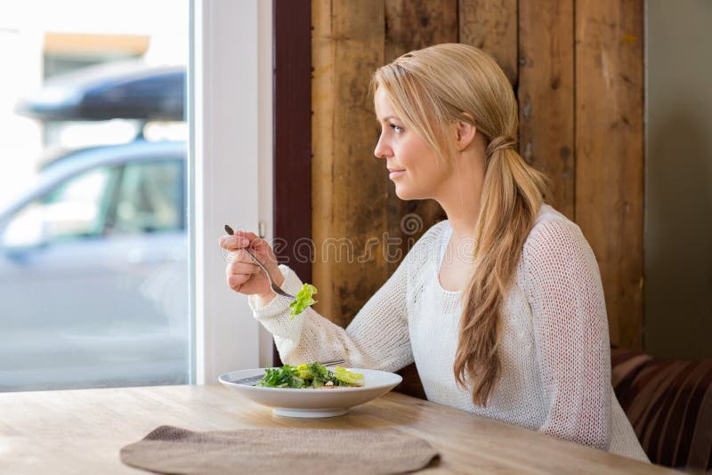 Woman Looking Through Window While Eating Salad stock images Woman Looking Through Window While Eating Salad stock images