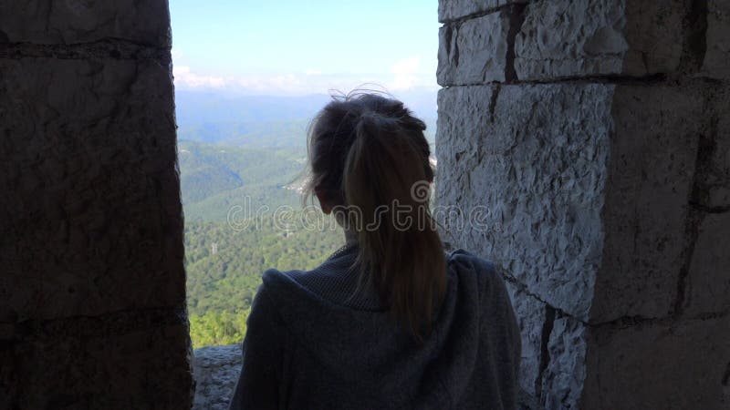 A woman looks at the mountains through a window on the observation tower.