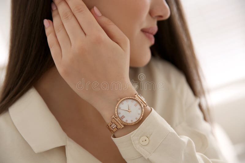 Woman with luxury wristwatch on blurred background