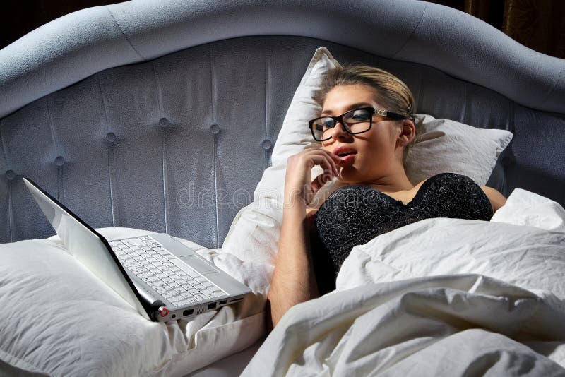 Woman lying on bed with a laptop