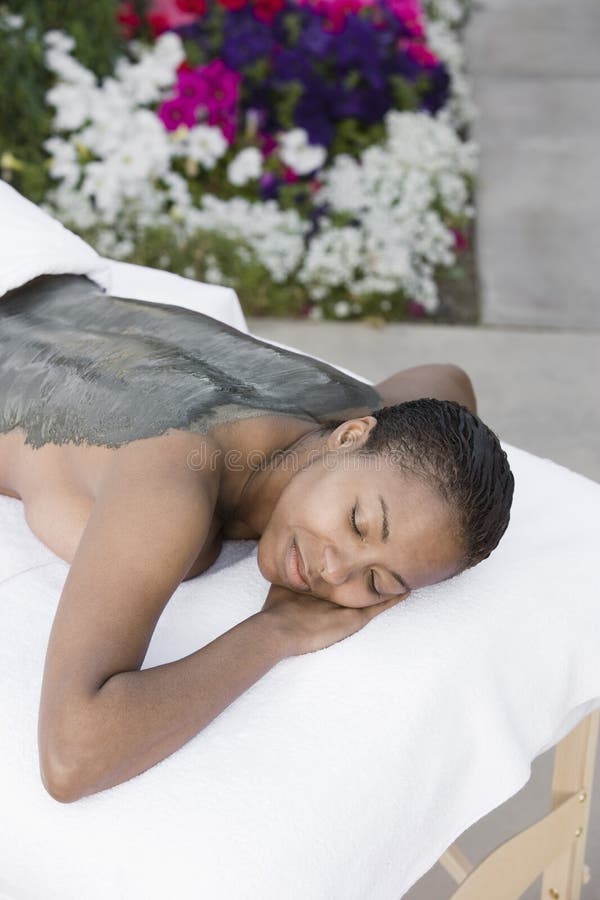 Woman Lying on Massage Bed with Mud Pack Applied on Back Stock Image