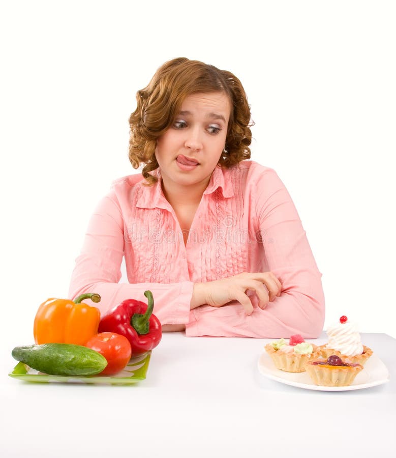 Woman makes choice of cakes and vegetables