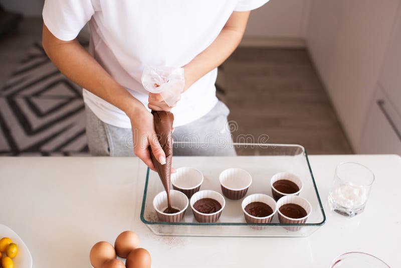 Woman baking chocolate cup cakes in glass tray in kitchen closeup. Young  girl put muffins in hot over. Female cooking tasty snack pastry at home.  Hea Stock Photo - Alamy