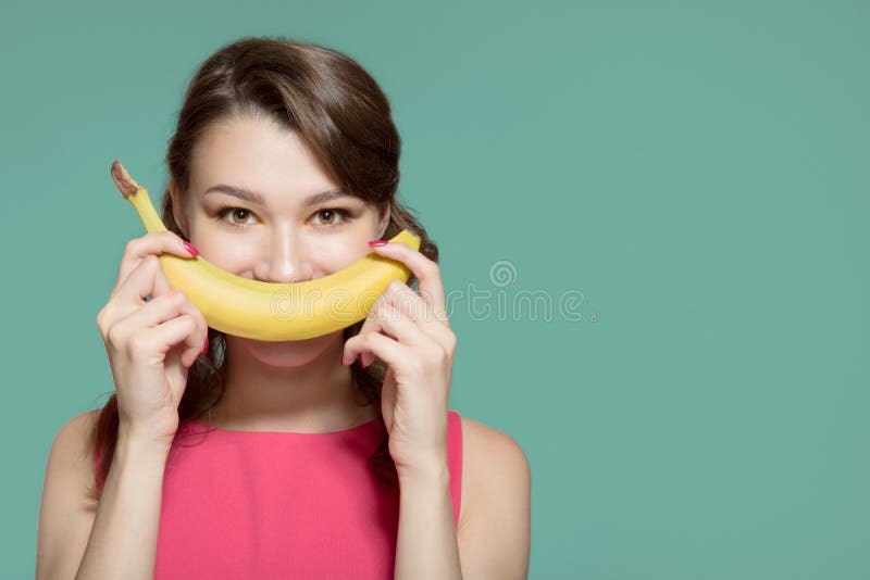 Woman making fun of banana. Turquoise background stock photography Woman making fun of banana. Turquoise background stock photography