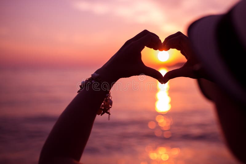 Woman making heart of hands near sea