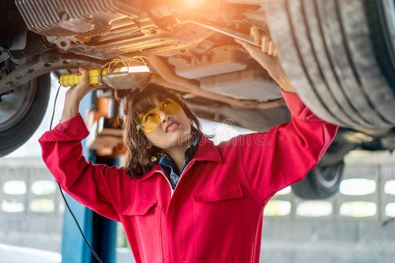 Woman Mechanic Examining Under The Car At The Repair Garage Stock Image