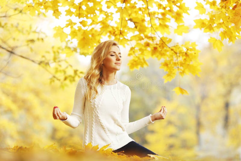 Woman meditating in autumn park