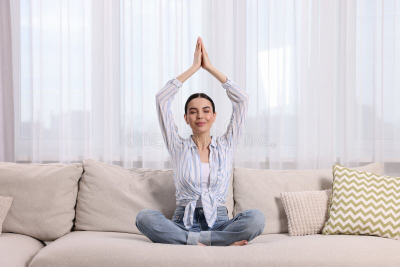 Woman meditating on sofa at home. Harmony and zen royalty free stock images