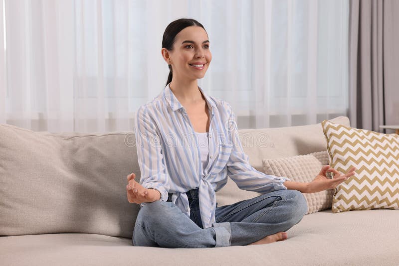 Woman meditating on sofa at home. Harmony and zen royalty free stock images