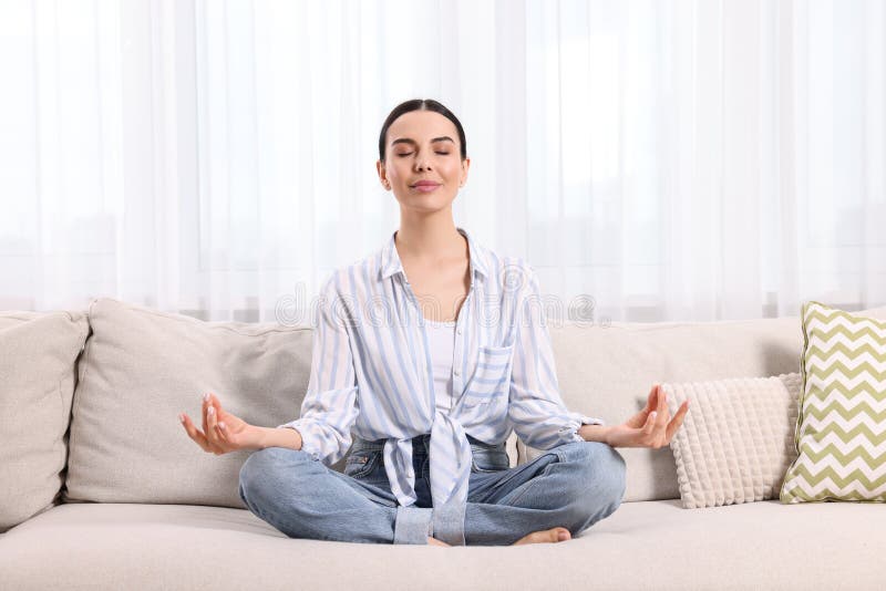 Woman meditating on sofa at home. Harmony and zen royalty free stock photo