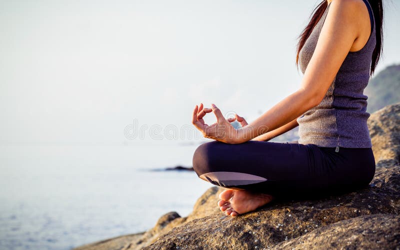 The woman meditating in a yoga pose on the tropical beach. Female meditating overlooking the beautiful sunrise. Healthy mind body