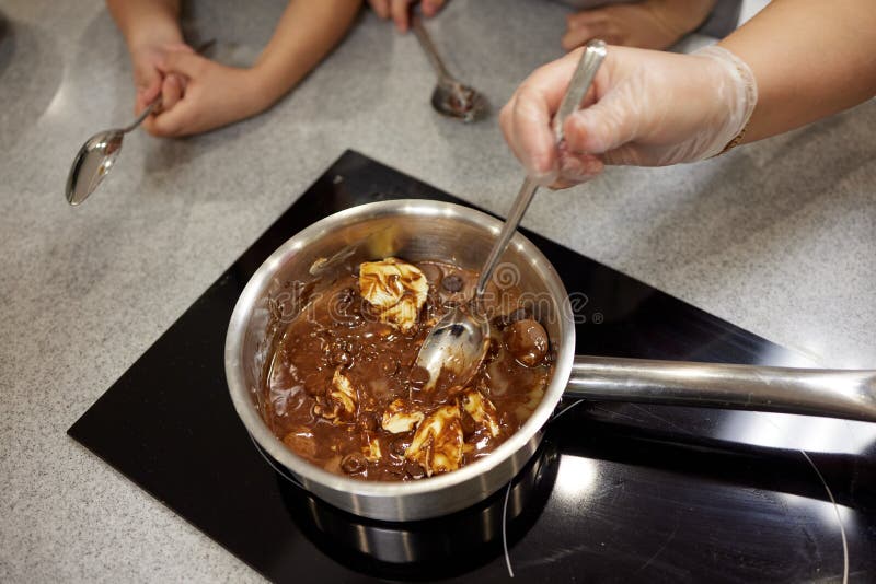 Woman melting chocolate in a pan and mix it with butter, close-up. Cooking at home, homemade sweet food.