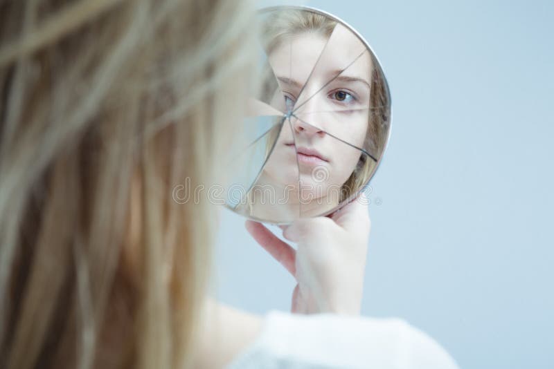 Obraz ženy s duševnou poruchou holding rozbité zrkadlo.