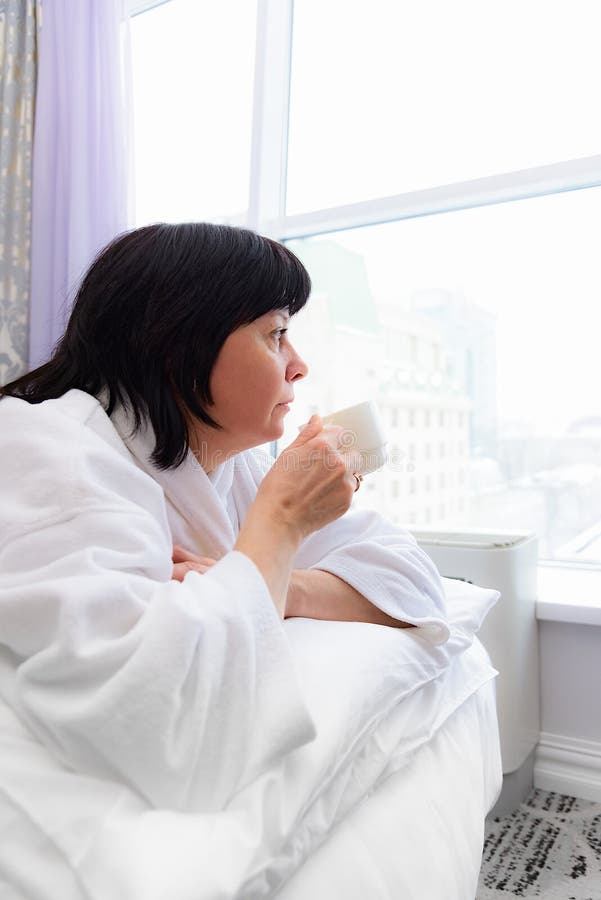 Woman in the morning in bed with a cup of coffee