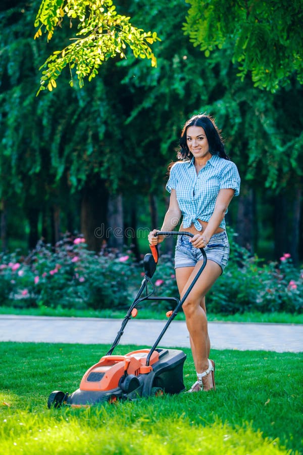 Woman mowing lawn in residential back garden stock photo.
