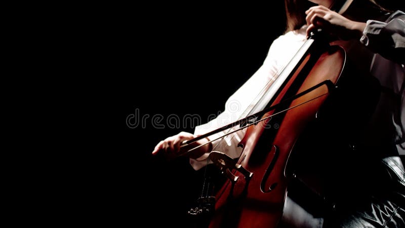 Woman musician plays music at cello. Female musician plays classical music on cello while sitting on chair in studio stock video footage