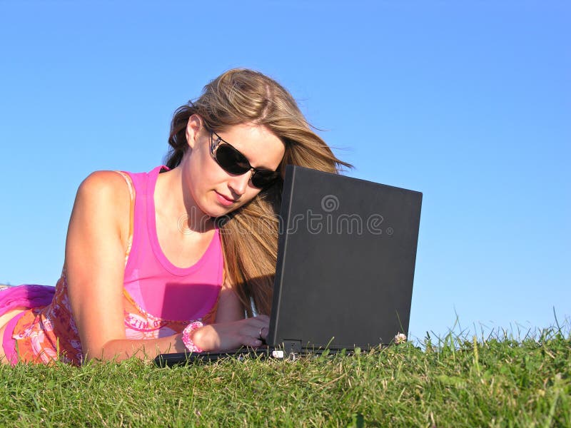 Frau mit notebook auf der wiese.