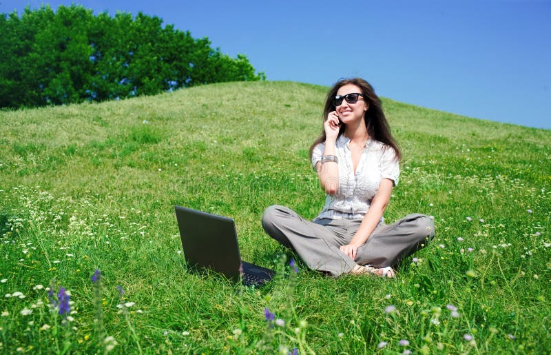 Woman with notebook and phone sit on hill