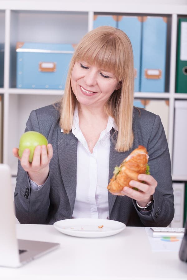 Woman at the office having lunch. Concept for healty or unhealthy food at work stock photography Woman at the office having lunch. Concept for healty or unhealthy food at work stock photography