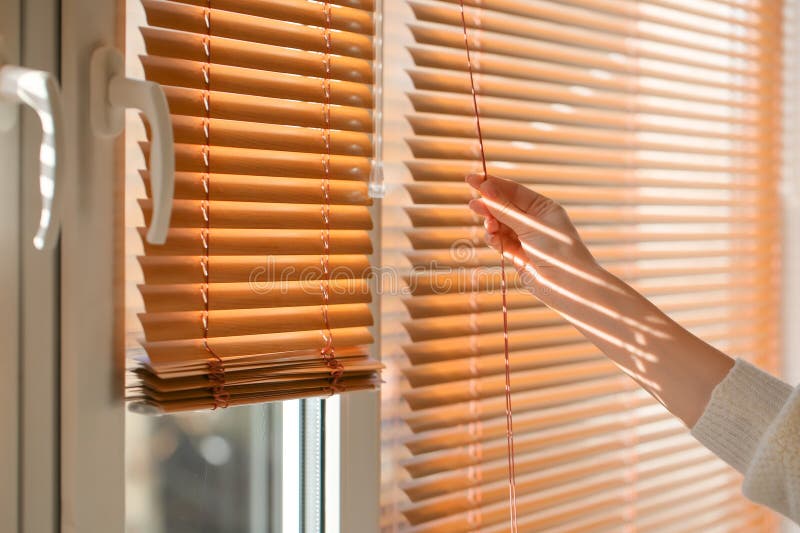 A lady is opening the window blinds. A lady is opening the window blinds