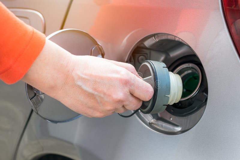 Woman opening the fuel tank of a car