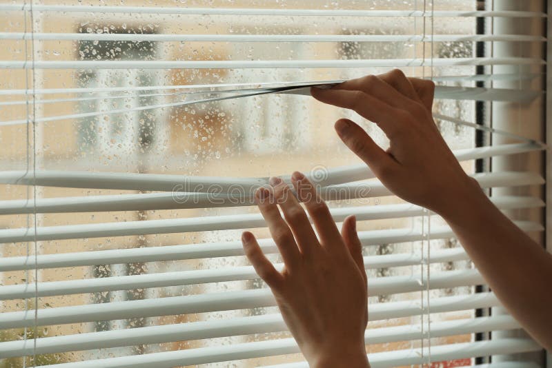 Woman opening window blinds, closeup. Space for text