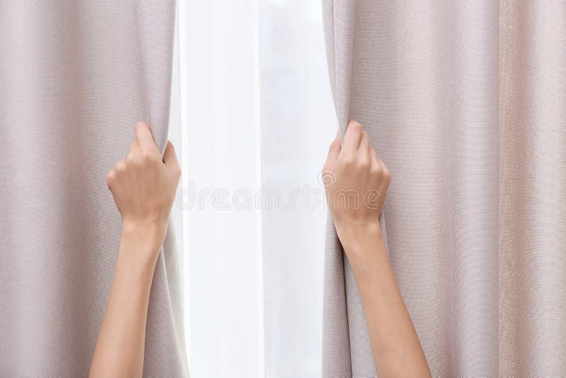 Woman opening window curtains at home, closeup