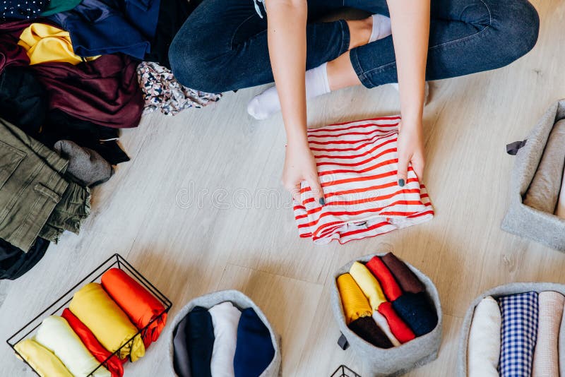 Woman folding pile of clothes on the floor, organizing stuff