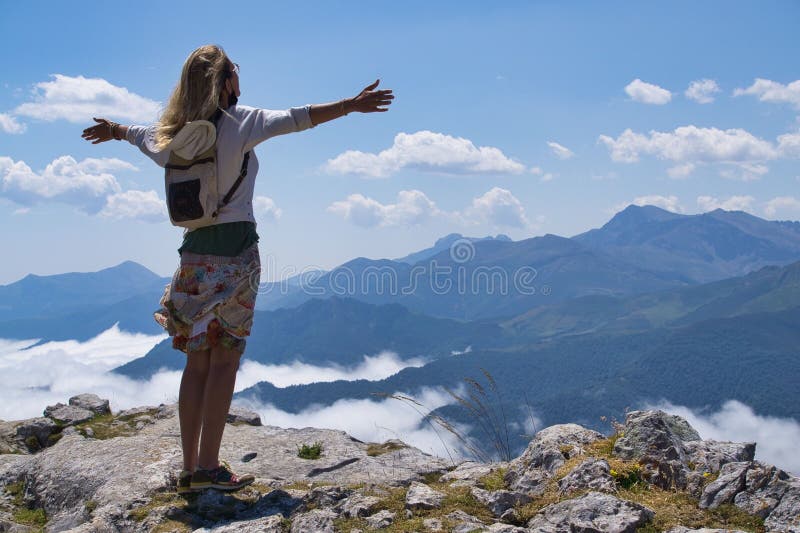 Woman with outstretched arms enjoys a scenic mountain view under a bright blue sky stock photography