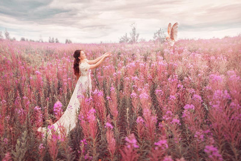 Woman with owl at field of pink flowers.