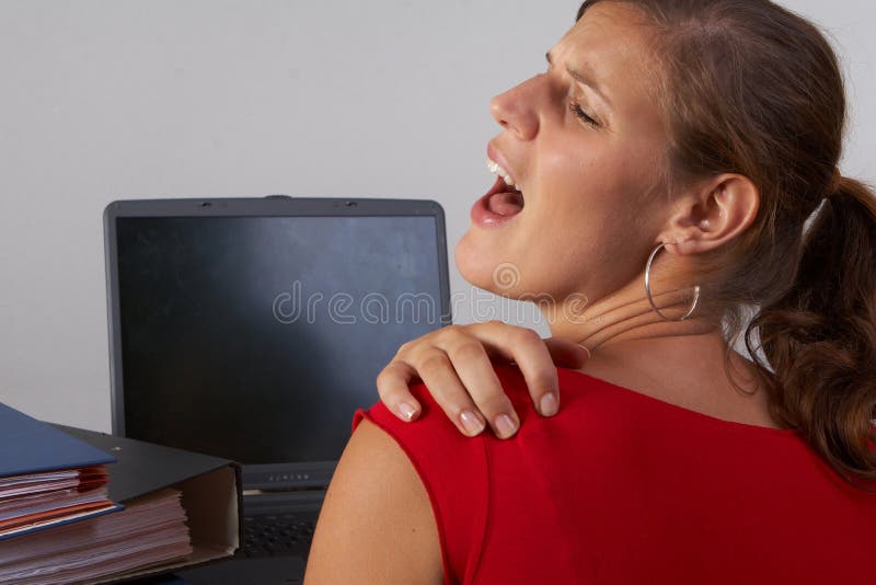 Young woman sitting at her laptop with a lot of work in front of her. She has a pain in her neck / back. Young woman sitting at her laptop with a lot of work in front of her. She has a pain in her neck / back.