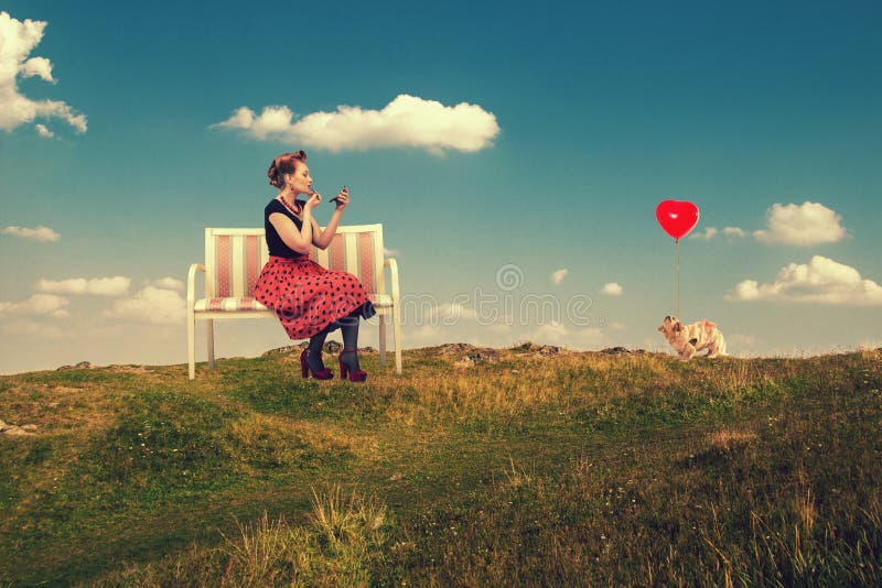 Woman paints lips with lipstick sitting on a couch in nature.