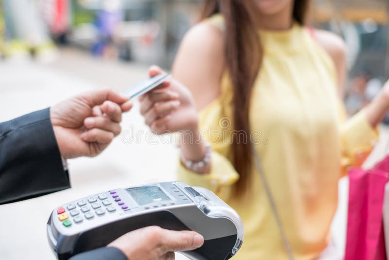 Woman paying credit card with payment terminal and cashier man