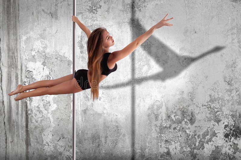 Woman performing pole dance. Shot with wall background royalty free stock image