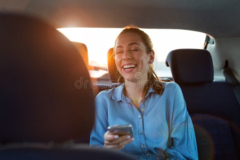 Woman with phone on the back seat of a car stock photos Woman with phone on the back seat of a car stock photos