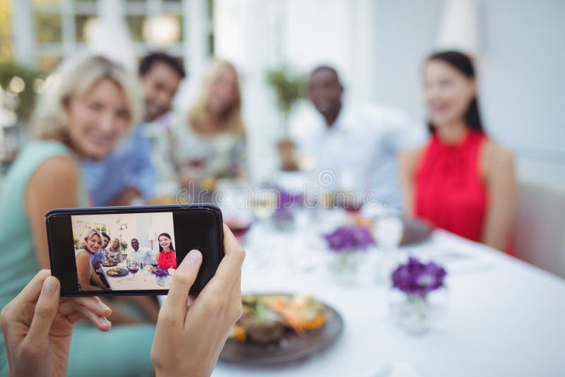 Woman photographing of friends sitting at table stock images