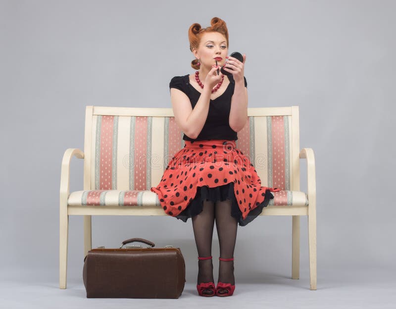 Woman in a pin-up paints lips with lipstick