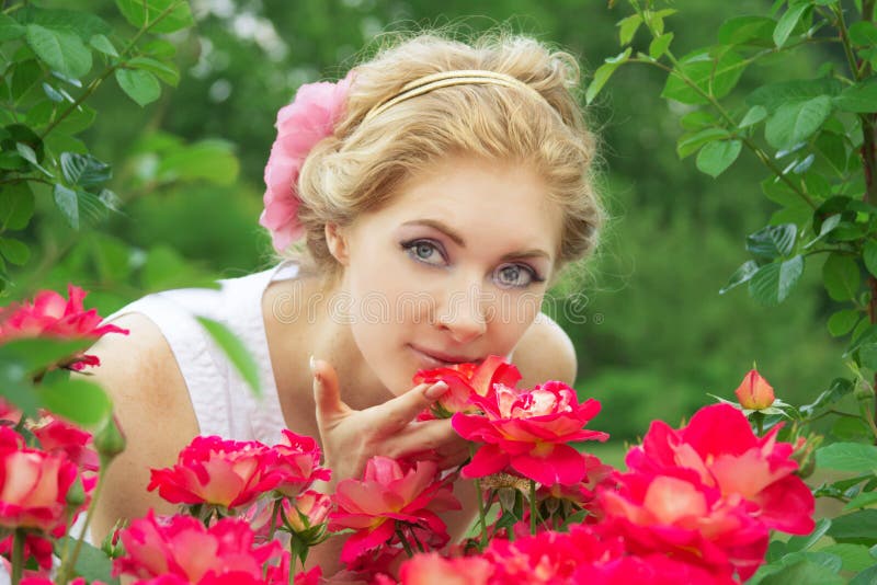 Woman in pink rose garden smelling