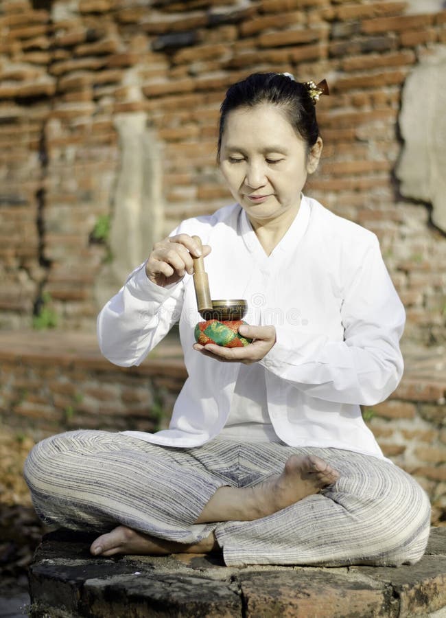 Woman playing a tibetan bowl, traditionally used to aid meditation in Buddhist cultures.