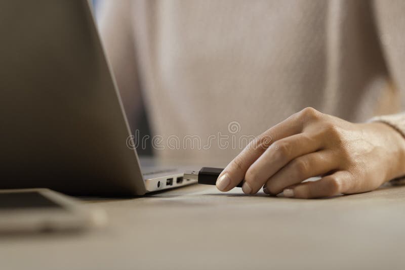 Woman plugging a USB flash drive into her laptop stock photography